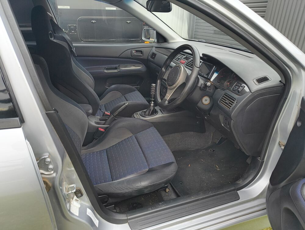 Driver cabin viewed from the passenger door — factory Recaros, OEM Momo, dash with Plex display
