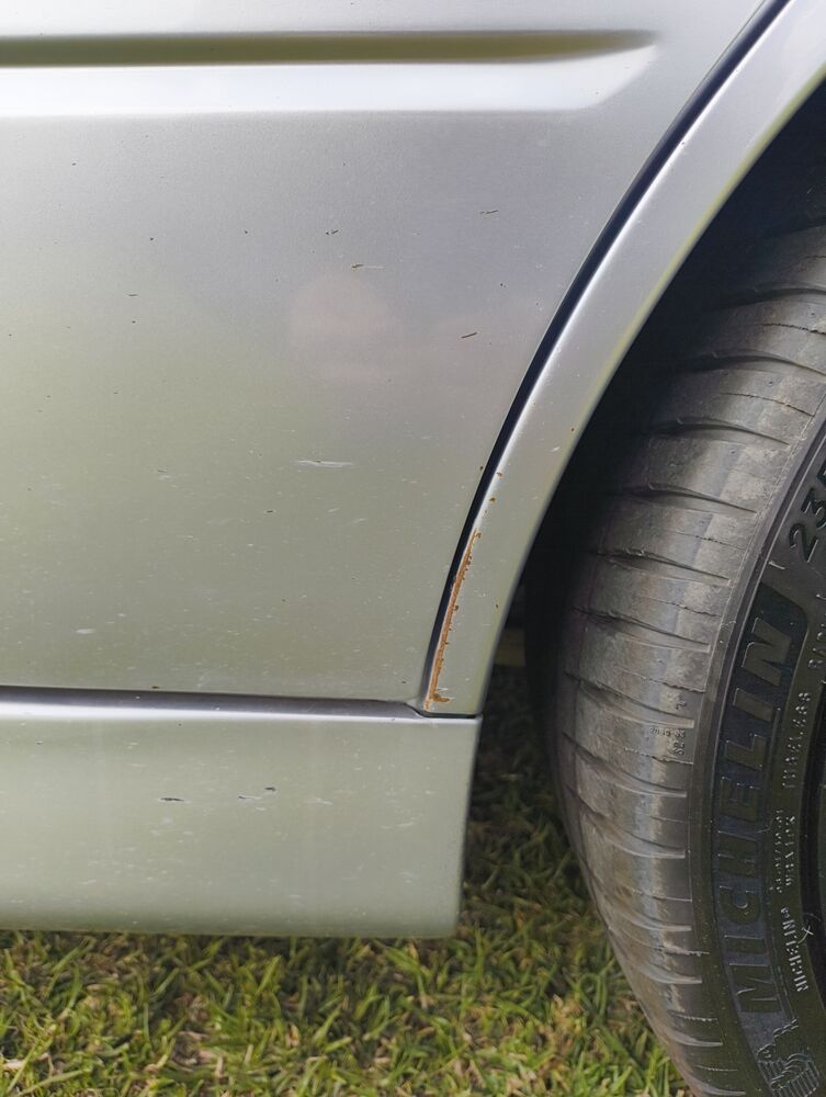 Paint chip with surface rust starting at the rear-quarter wheel arch